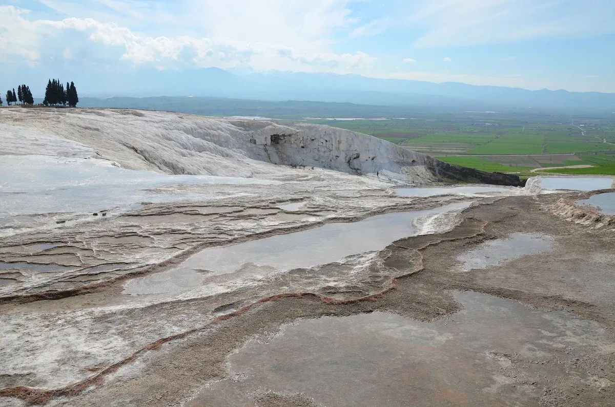Water pooling on the white travertine terraces of Pamukkale above the Denizli plain, a stop on Turkey tour packages